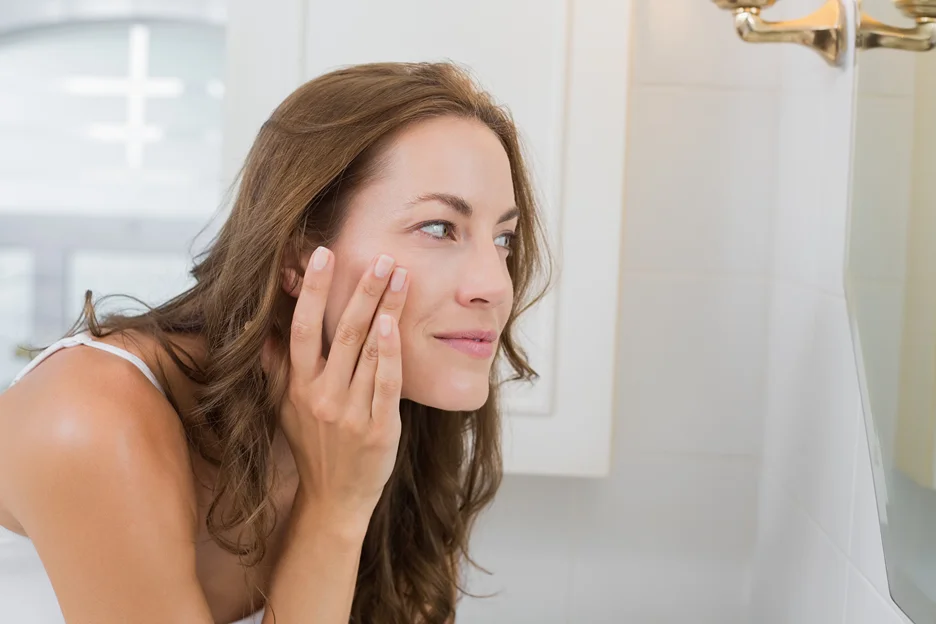 a woman examines her face 