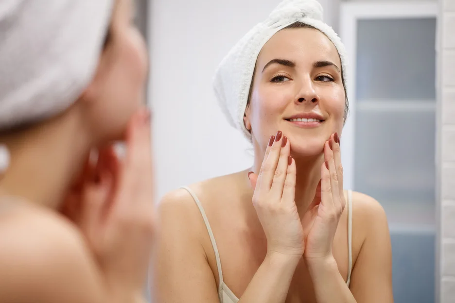 a woman checks her face in front of the mirror after salmon dna injections